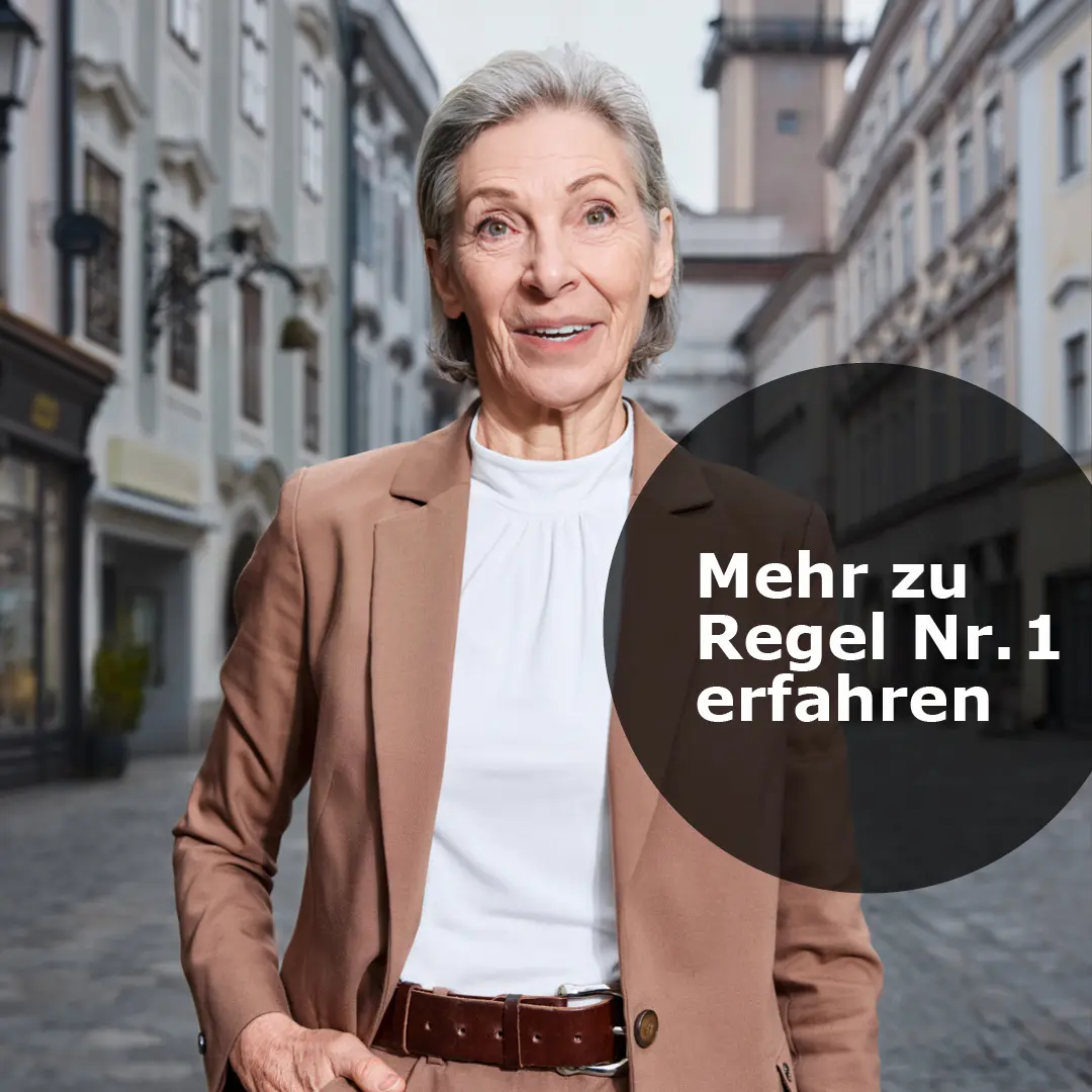 Ältere Frau in beigefarbenem Blazer steht auf gepflasterter Straße in einer Altstadt.